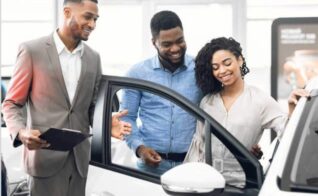 A car salesman showing a couple the details of a car.